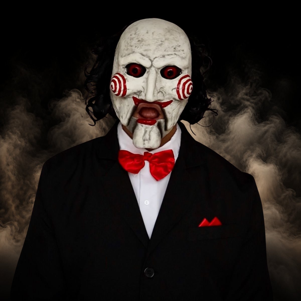 Creepy puppet halloween mask with red spiral cheeks worn with a black suit and red bow tie