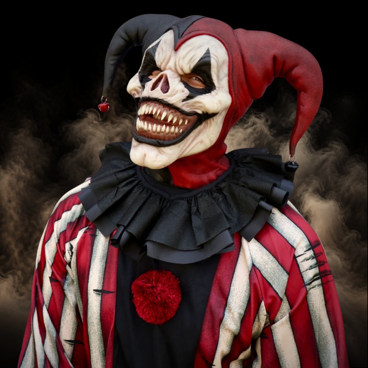 Evil jester clown mask with a red and black hat and a wide toothy grin